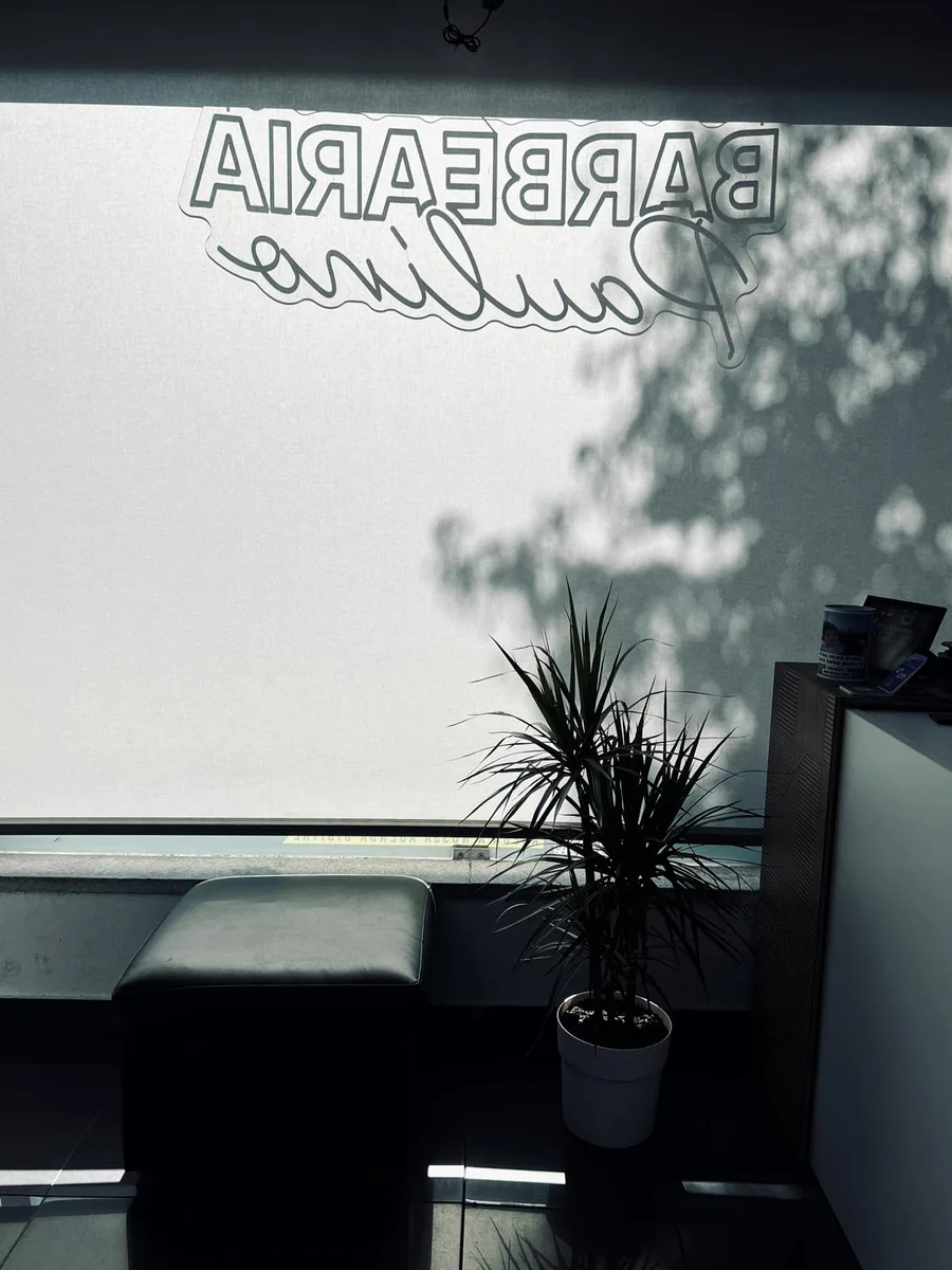 Reflexo do letreiro Barbearia Paulino